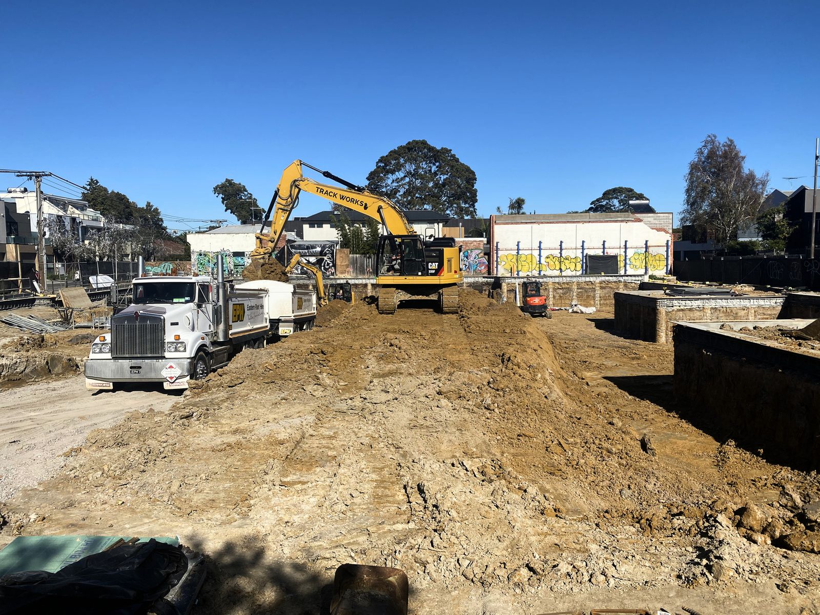 Track Works excavator loading a truck on a suburban site