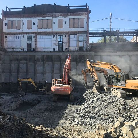 Excavators working a rock face below a heritage facade